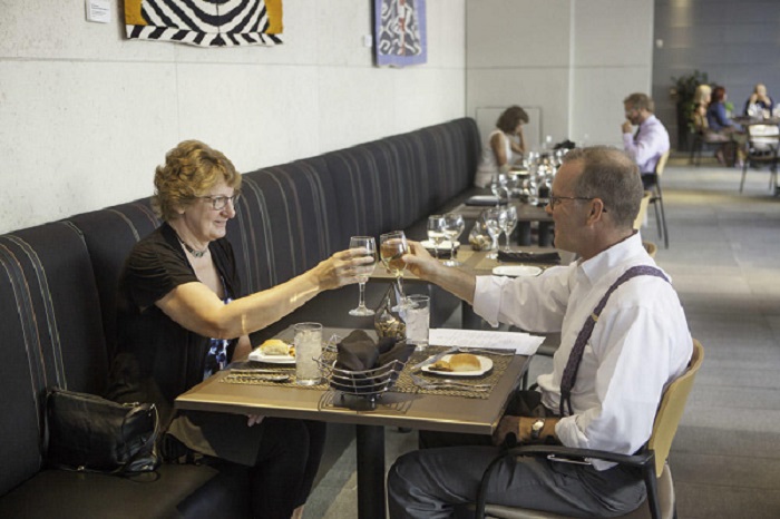 A smiling couple dining in Zinc clinks their glasses together in cheers. 